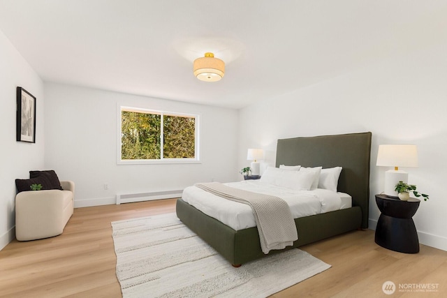 bedroom with light wood-style flooring, a baseboard heating unit, and baseboards