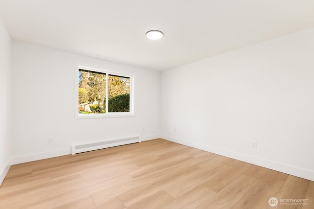 empty room with light wood-type flooring, baseboards, and a baseboard heating unit