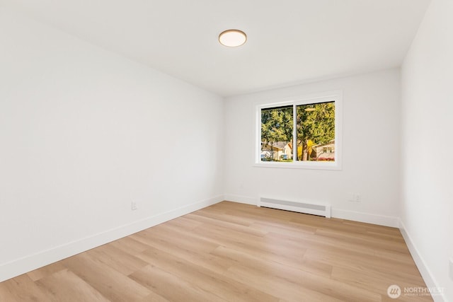 unfurnished room featuring light wood-style flooring, baseboards, and baseboard heating