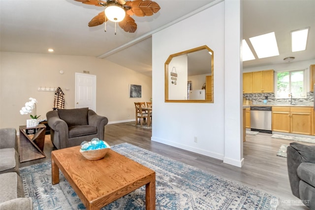 living room with light wood-type flooring, lofted ceiling, baseboards, and ceiling fan