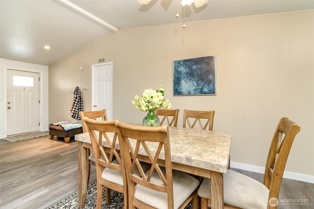 dining area featuring lofted ceiling with beams, baseboards, wood finished floors, and a ceiling fan