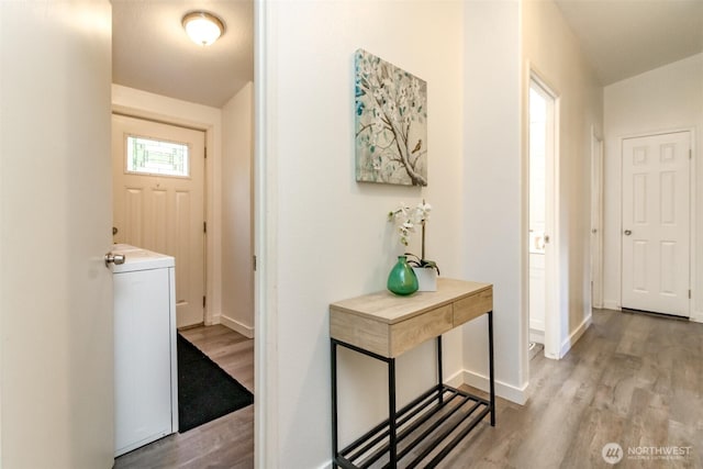 hall with light wood-style flooring, washer / clothes dryer, and baseboards