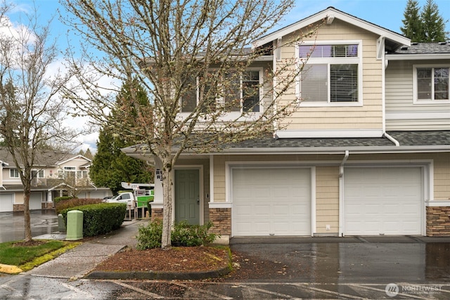 multi unit property featuring driveway, stone siding, a shingled roof, and an attached garage