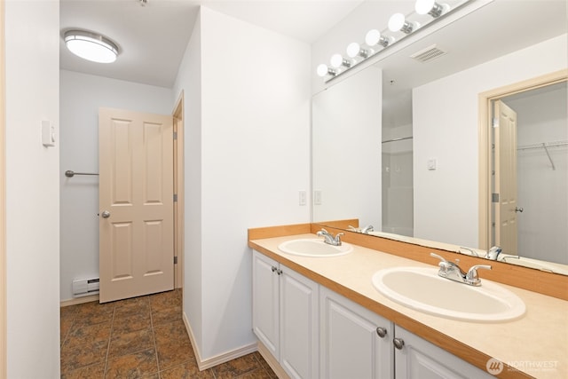 full bathroom featuring stone finish floor, a baseboard heating unit, visible vents, and a sink