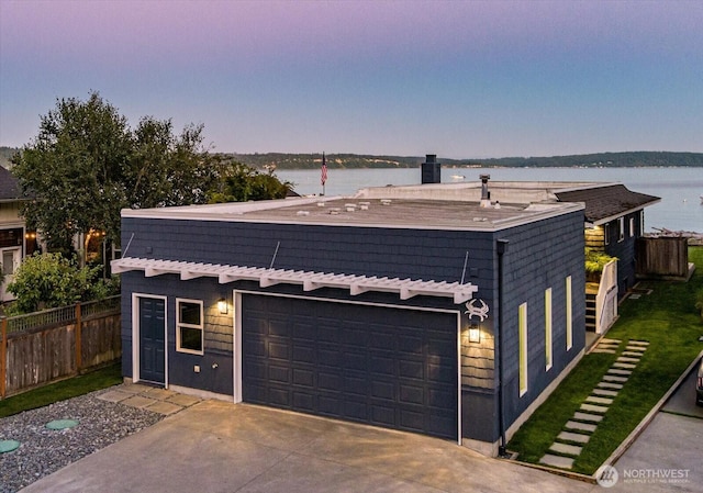 view of front of property featuring a garage, a water view, driveway, and fence