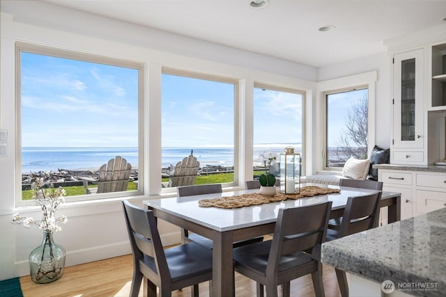 dining space featuring light wood finished floors, recessed lighting, and a water view