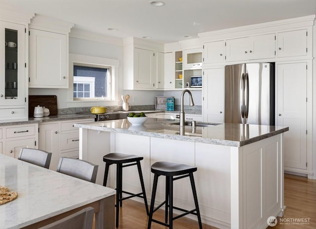 kitchen featuring a breakfast bar, white cabinetry, freestanding refrigerator, and a sink