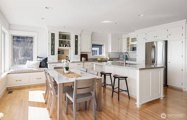 kitchen with white cabinetry, light wood-style flooring, an island with sink, and a sink