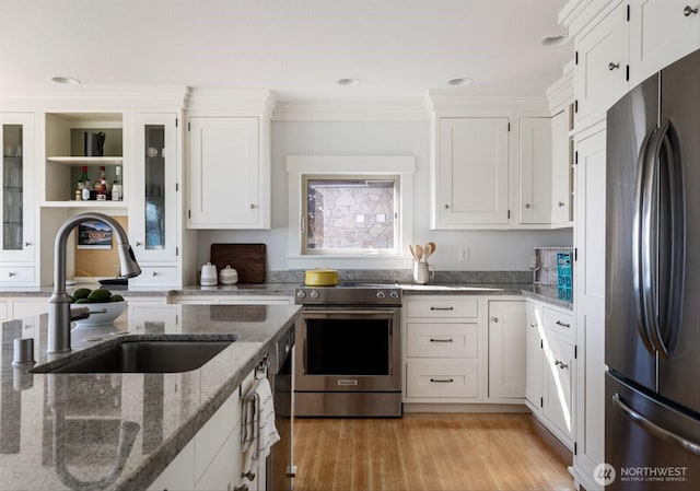 kitchen with light wood-type flooring, a sink, stainless steel appliances, white cabinets, and crown molding