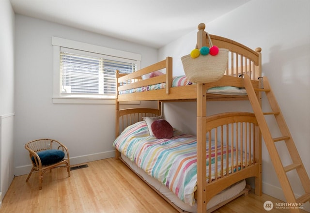 bedroom featuring wood finished floors, visible vents, and baseboards