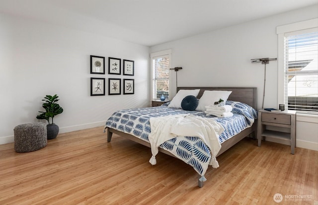 bedroom with multiple windows, baseboards, and light wood finished floors