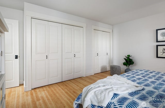 bedroom featuring light wood-style flooring and two closets