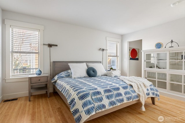 bedroom with visible vents, baseboards, and wood finished floors