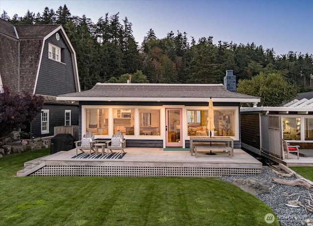 back of property with a yard, a gambrel roof, a chimney, and an outdoor hangout area