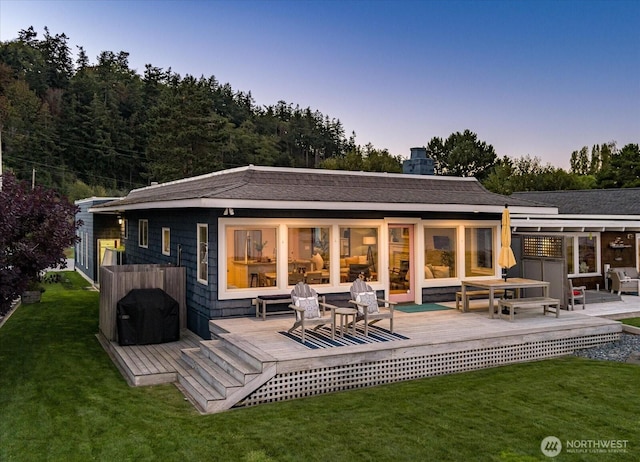 rear view of house with a wooden deck and a yard