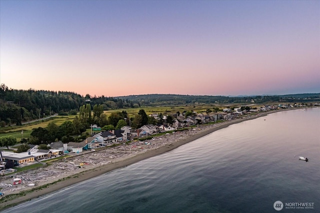 aerial view at dusk featuring a water view