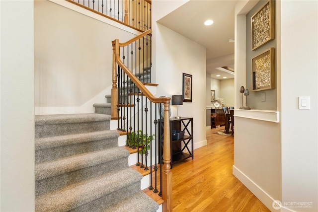 stairway with recessed lighting, wood finished floors, and baseboards