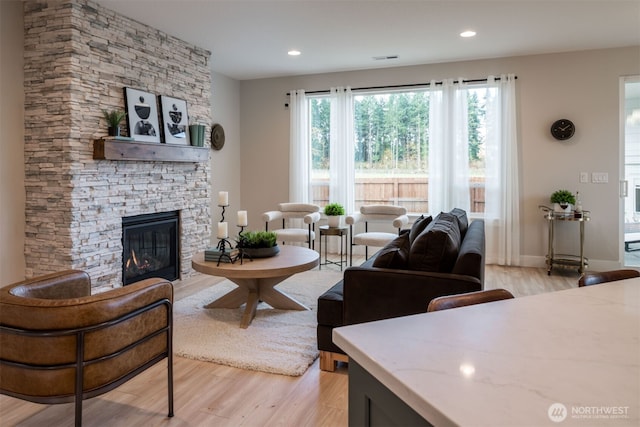 living area with baseboards, light wood-type flooring, a fireplace, and recessed lighting