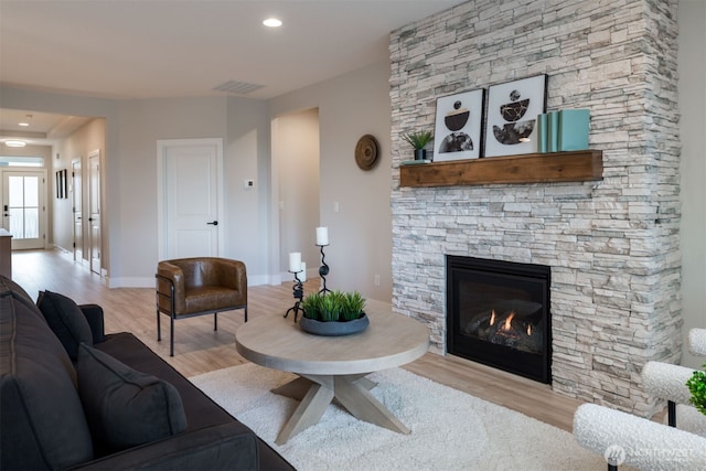 living room with recessed lighting, visible vents, a stone fireplace, wood finished floors, and baseboards