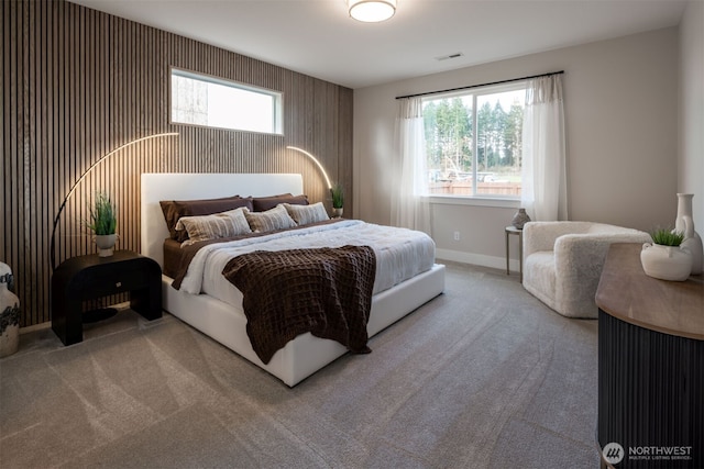 carpeted bedroom with an accent wall, baseboards, multiple windows, and visible vents