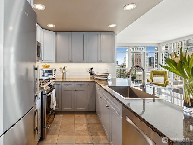 kitchen with a sink, dark stone counters, recessed lighting, and stainless steel appliances