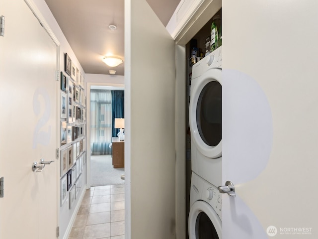 laundry area featuring laundry area, light tile patterned flooring, and stacked washer and clothes dryer