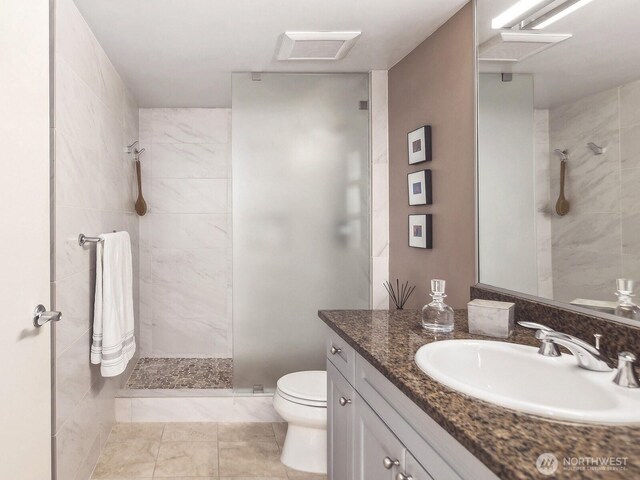 full bathroom with vanity, toilet, a walk in shower, and visible vents