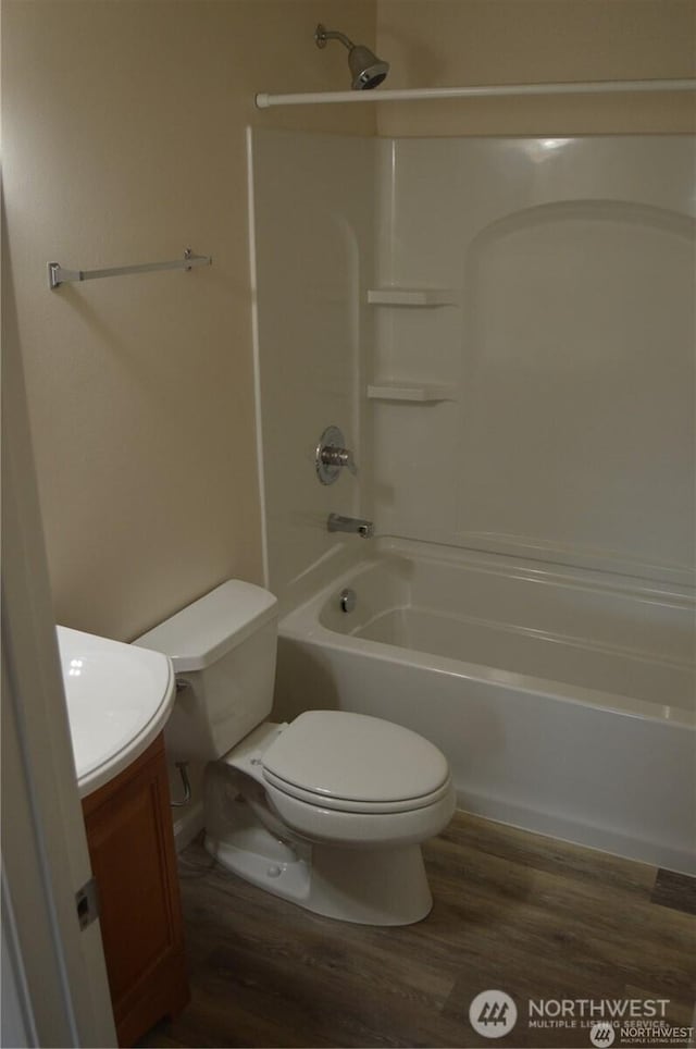 bathroom with toilet, shower / tub combination, wood finished floors, and vanity