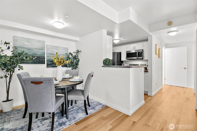 dining area featuring light wood-type flooring and baseboards