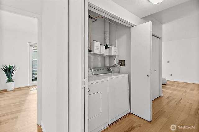 washroom featuring baseboards, laundry area, light wood-type flooring, and washer and dryer