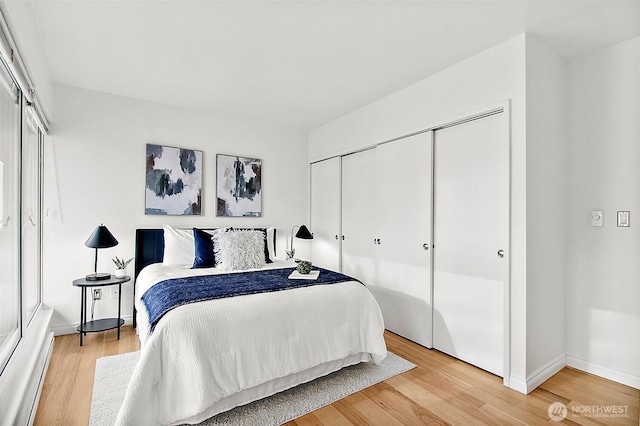 bedroom with a closet, baseboards, and light wood finished floors