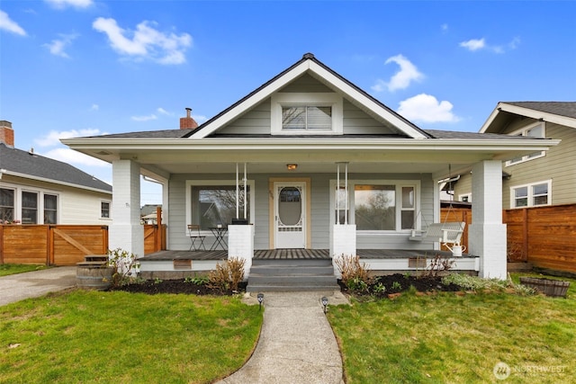 bungalow-style house with covered porch, a front yard, fence, and a gate