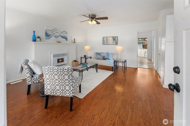 living room with ceiling fan, a fireplace, visible vents, and wood finished floors