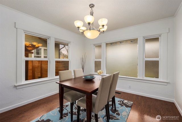 dining space featuring a textured ceiling, a notable chandelier, dark wood-style flooring, baseboards, and crown molding