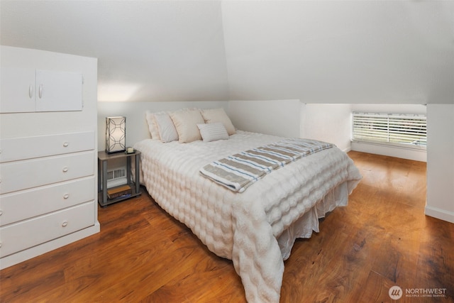 bedroom with vaulted ceiling and dark wood finished floors