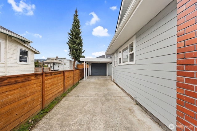 view of home's exterior featuring a garage, concrete driveway, and fence