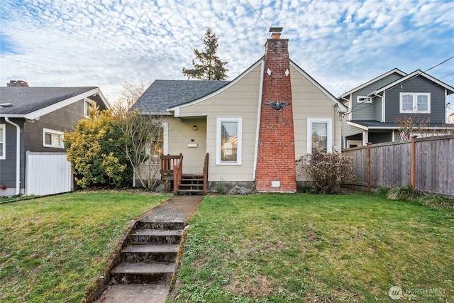 view of front facade featuring a chimney, roof with shingles, a front lawn, and fence