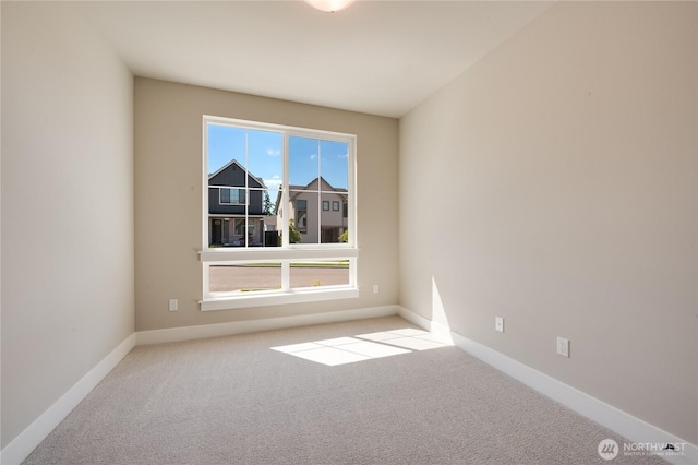 unfurnished room featuring carpet floors, a wealth of natural light, and baseboards