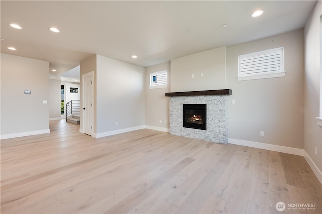 unfurnished living room featuring light wood-type flooring, a fireplace, baseboards, and recessed lighting