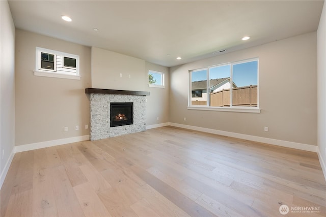 unfurnished living room featuring a stone fireplace, recessed lighting, wood finished floors, visible vents, and baseboards