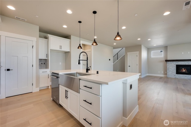 kitchen featuring visible vents, a sink, light wood finished floors, and stainless steel dishwasher