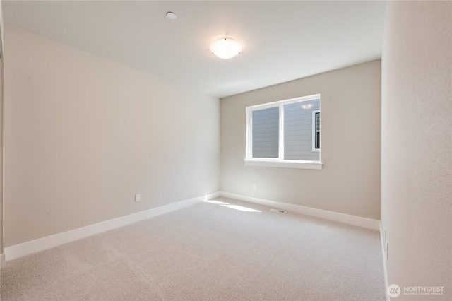 carpeted spare room featuring visible vents and baseboards