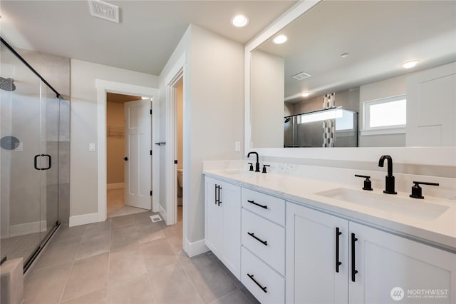 bathroom with double vanity, a stall shower, visible vents, and a sink