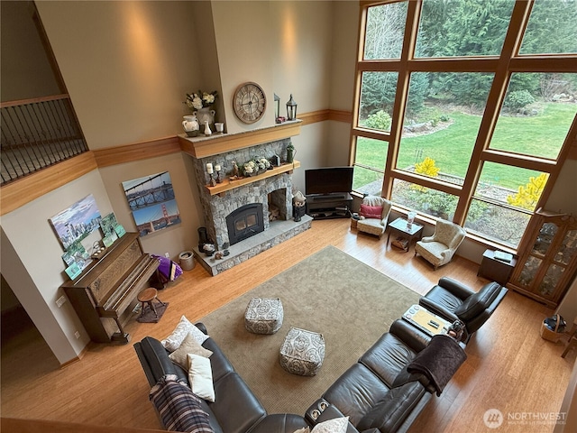 living area with a fireplace, wood finished floors, and a towering ceiling