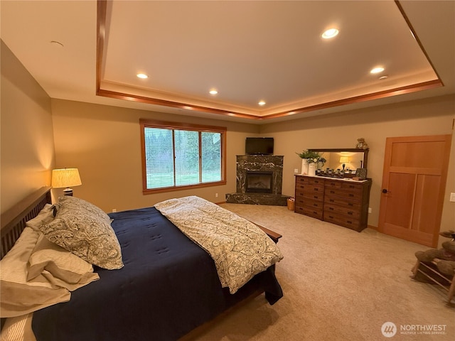 carpeted bedroom with a raised ceiling, a high end fireplace, and recessed lighting