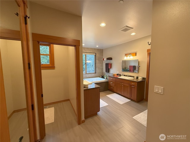 bathroom featuring recessed lighting, wood finished floors, vanity, visible vents, and a bath