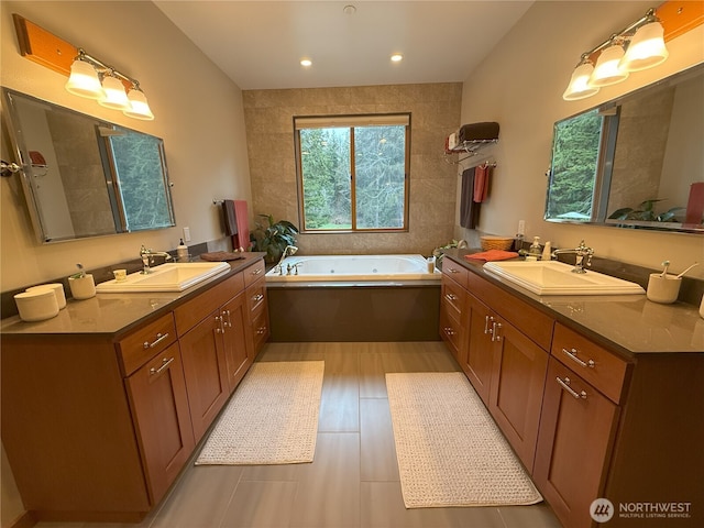 full bath featuring a garden tub, two vanities, and a sink