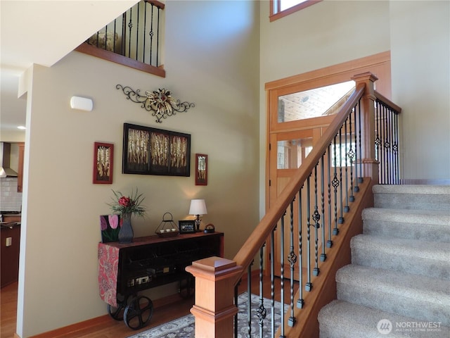 stairway with a high ceiling and wood finished floors