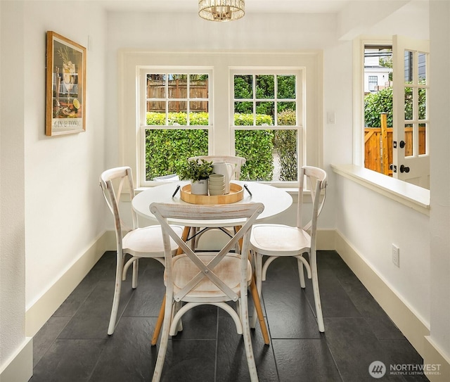 dining area featuring dark tile patterned floors and baseboards