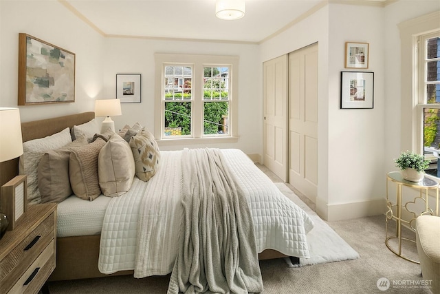 carpeted bedroom with a closet, baseboards, and ornamental molding